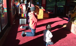 Young sangha members do their prostrations before the statue of Maitreya Buddha at the Wish-Fulfulling Temple.
