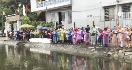 Disciples stand in the rain at the CoCo River for ceremony to liberate captive living beings after the Kuan Yin Empowerment in Da Nang, Vietnam.