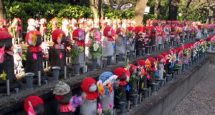 Jizo Statues at the cemetery in the Zojoji-temple in Tokyo, Japan, wearing bibs and other offerings for deceased children and fetuses.